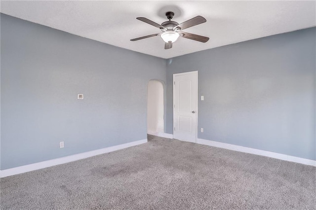 unfurnished room featuring arched walkways, carpet floors, a ceiling fan, and baseboards