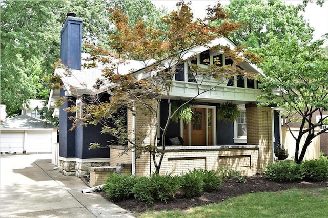 view of front facade featuring an outbuilding, a porch, brick siding, and a garage