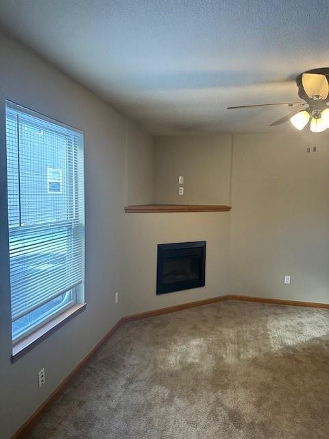 unfurnished living room featuring carpet floors, a fireplace, and baseboards