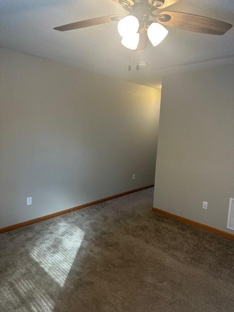 unfurnished room featuring a ceiling fan, visible vents, baseboards, and carpet flooring