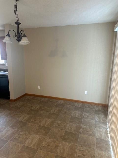 spare room with baseboards and a notable chandelier