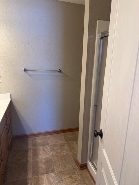 bathroom with a stall shower, vanity, and baseboards