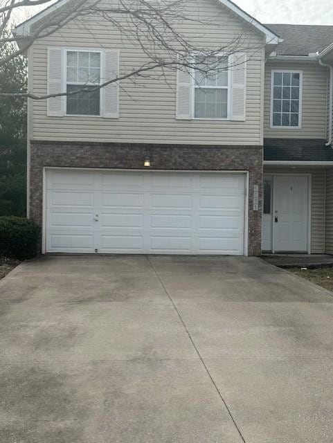 view of front of home with brick siding, a garage, and driveway