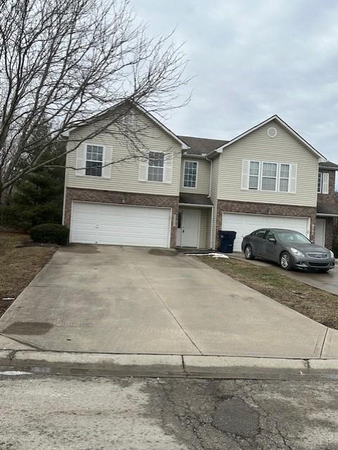 view of front of home featuring a garage, brick siding, and driveway