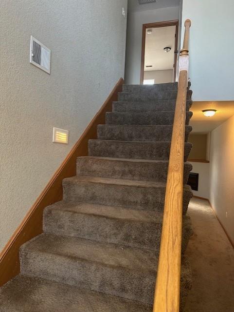 stairway with visible vents and carpet floors