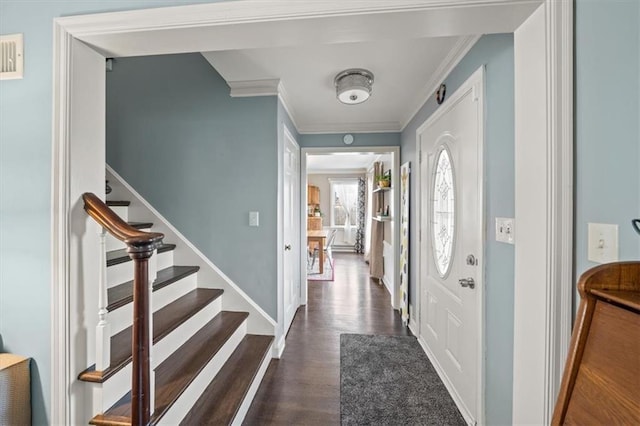 foyer entrance featuring ornamental molding, dark wood-type flooring, stairway, and baseboards