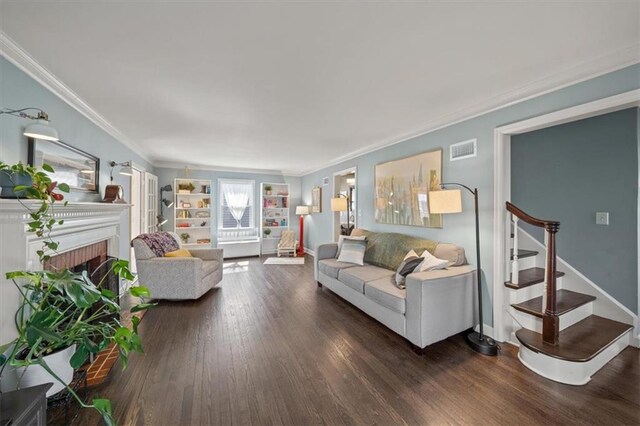 living area featuring a fireplace, wood finished floors, visible vents, stairs, and crown molding