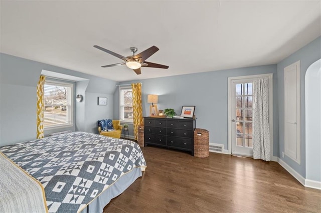 bedroom with arched walkways, ceiling fan, wood finished floors, visible vents, and baseboards