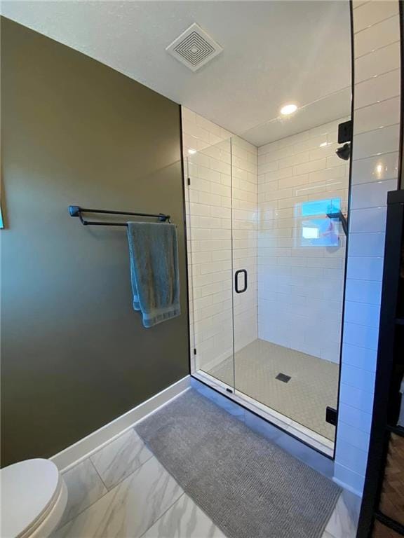 bathroom with marble finish floor, visible vents, toilet, a stall shower, and baseboards