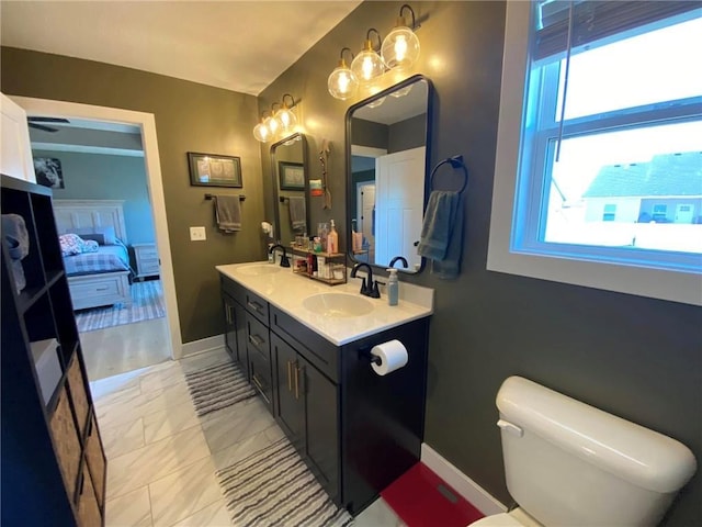 bathroom featuring double vanity, marble finish floor, connected bathroom, and a sink