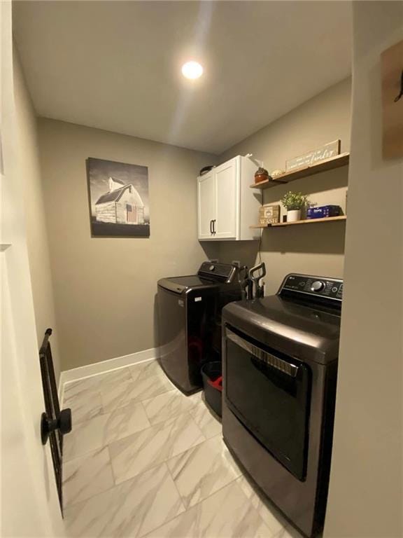 washroom featuring cabinet space, washing machine and dryer, marble finish floor, and baseboards