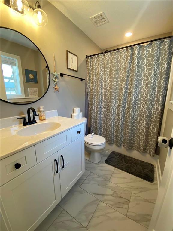 bathroom with marble finish floor, a shower with shower curtain, vanity, and visible vents