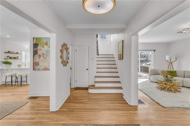 interior space featuring light wood-type flooring, visible vents, baseboards, and stairs