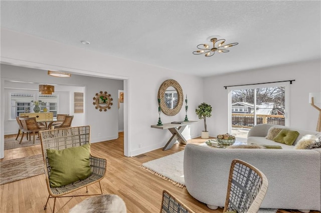 living room with baseboards, a textured ceiling, and light wood-style floors