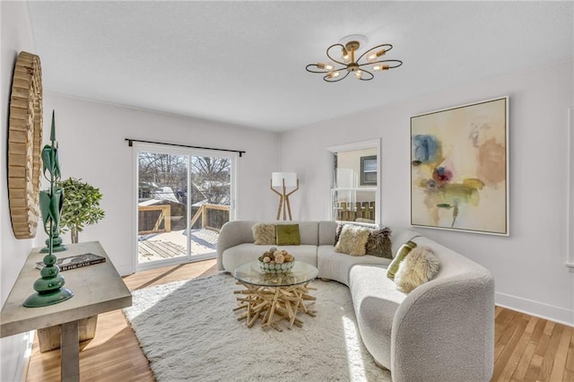 living room featuring baseboards, light wood finished floors, and an inviting chandelier