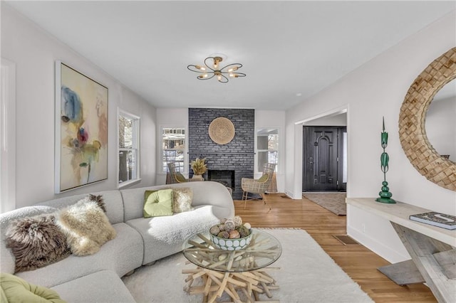 living room featuring a brick fireplace, wood finished floors, and baseboards