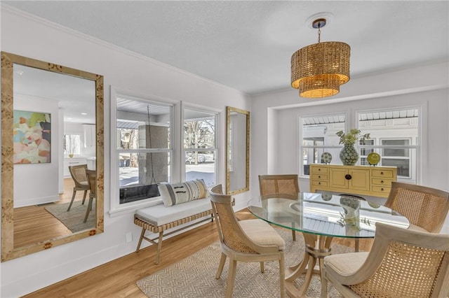 dining room featuring baseboards, ornamental molding, light wood-style flooring, and an inviting chandelier