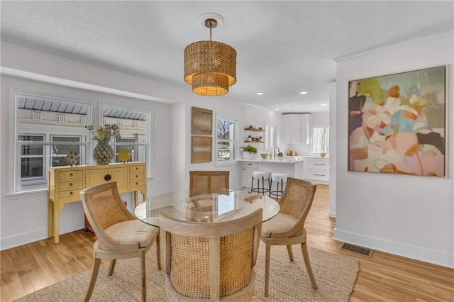 dining area featuring light wood-type flooring, visible vents, and baseboards