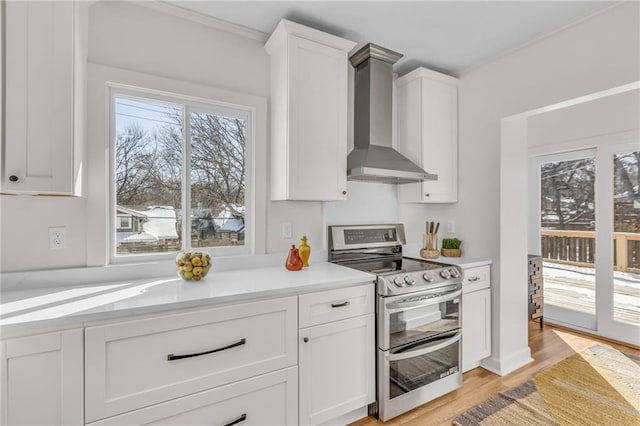 kitchen with range with two ovens, white cabinets, light countertops, and wall chimney exhaust hood