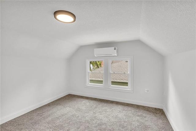 additional living space with lofted ceiling, a wall unit AC, a textured ceiling, and baseboards