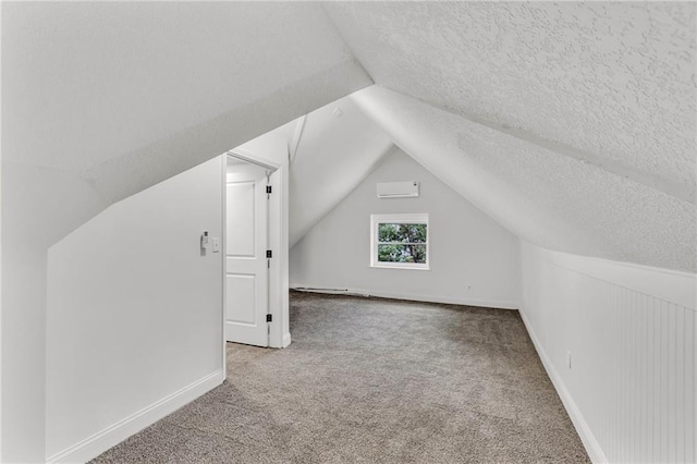 additional living space with lofted ceiling, a wall mounted air conditioner, a textured ceiling, and carpet flooring