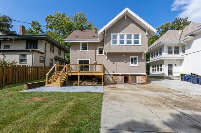 back of house with fence, a yard, a deck, and stucco siding