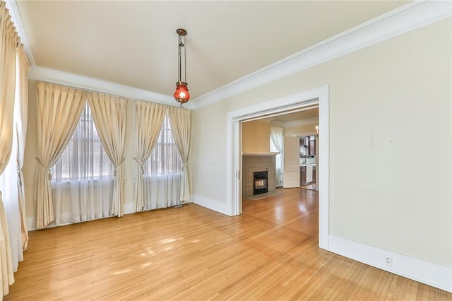 interior space featuring light wood-type flooring, a fireplace with flush hearth, ornamental molding, and baseboards