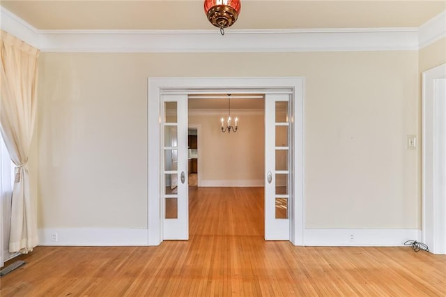 spare room featuring french doors, crown molding, visible vents, an inviting chandelier, and light wood-style floors