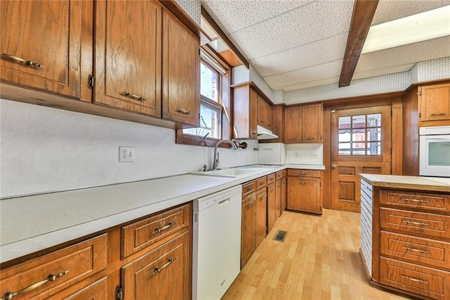 kitchen featuring white appliances, plenty of natural light, and brown cabinets