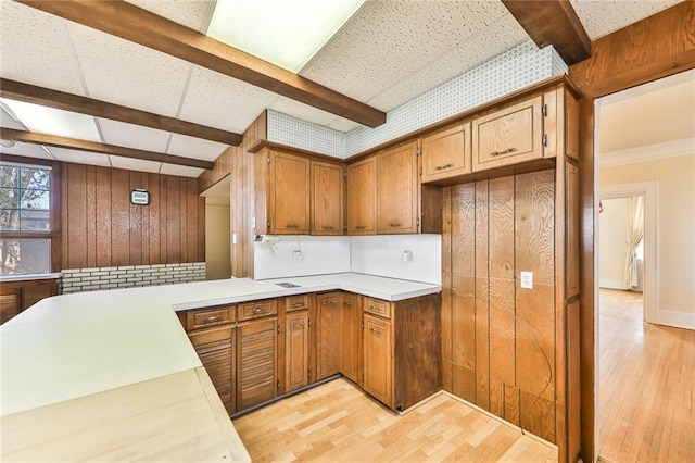 kitchen with light wood-style floors, light countertops, beam ceiling, and brown cabinets