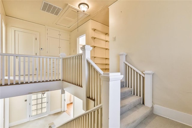 staircase with attic access, visible vents, and baseboards