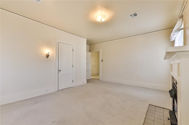 unfurnished living room with light carpet, a fireplace, visible vents, and baseboards