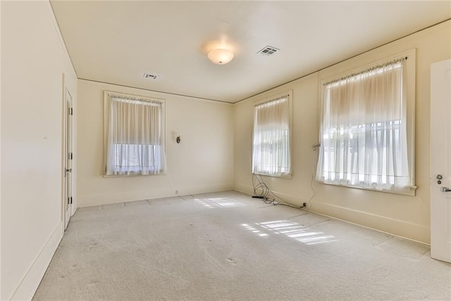 carpeted spare room featuring baseboards and visible vents