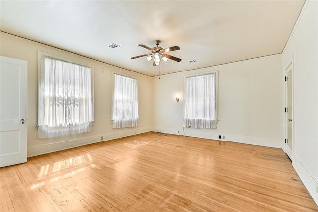 empty room with light wood finished floors, baseboards, visible vents, and a ceiling fan