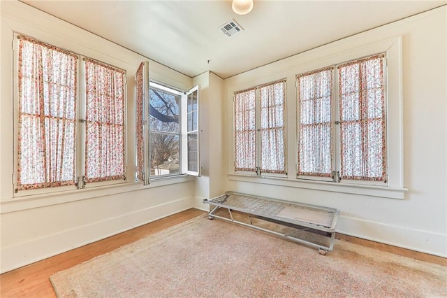 spare room featuring visible vents, baseboards, and wood finished floors