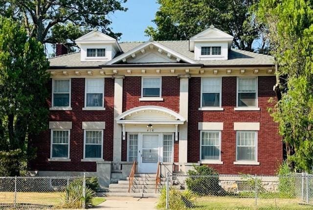 view of front facade with entry steps, a fenced front yard, and brick siding