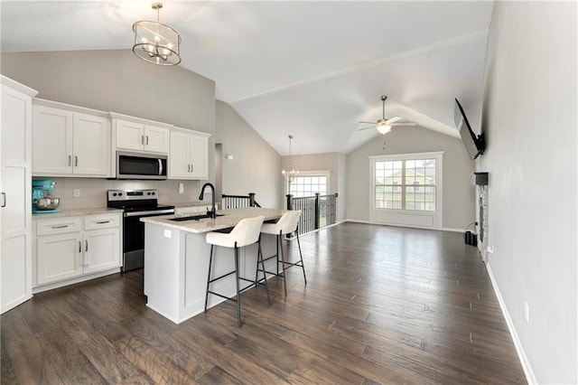 kitchen with appliances with stainless steel finishes, a kitchen island with sink, white cabinetry, and hanging light fixtures