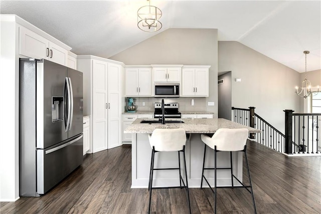 kitchen with stainless steel appliances, hanging light fixtures, white cabinetry, a sink, and a chandelier