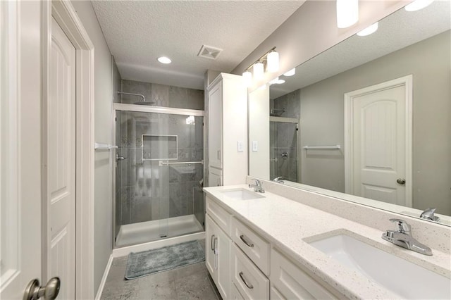 bathroom with double vanity, a stall shower, visible vents, and a sink