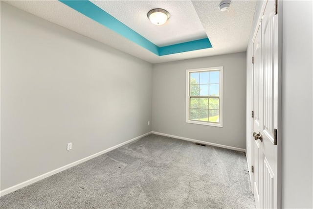 spare room with light carpet, visible vents, baseboards, and a textured ceiling