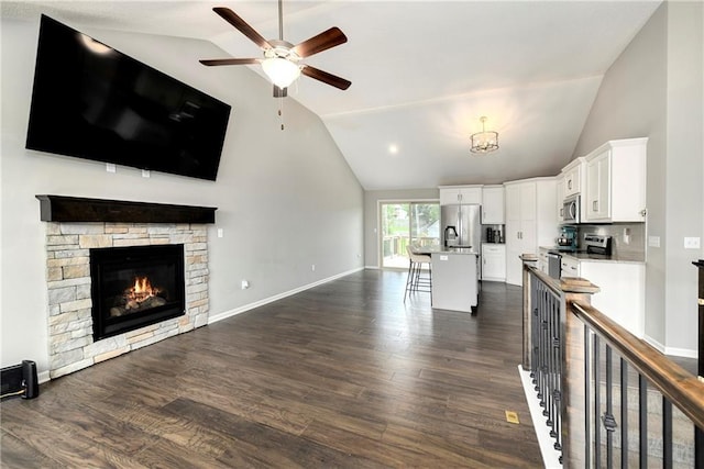 kitchen featuring open floor plan, a kitchen breakfast bar, stainless steel appliances, light countertops, and white cabinetry