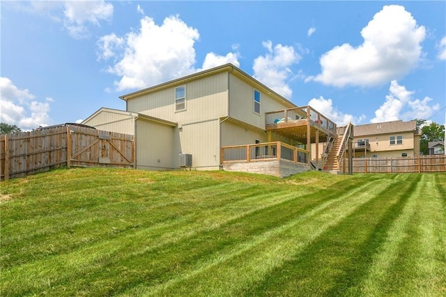 back of house with a fenced backyard, a lawn, a deck, and stairs