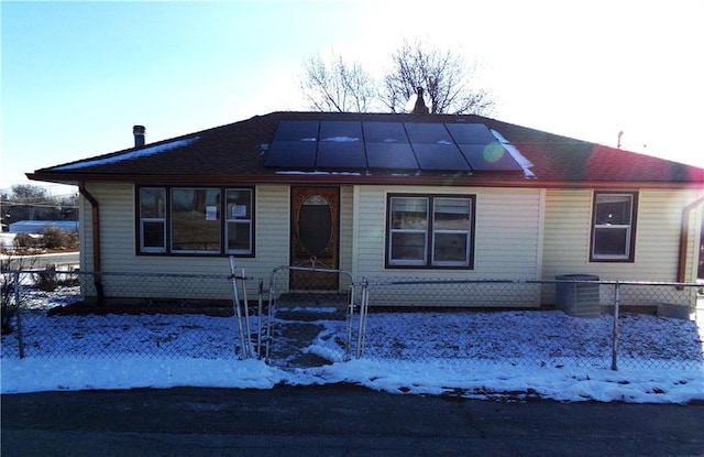 view of front facade featuring cooling unit, fence, and solar panels