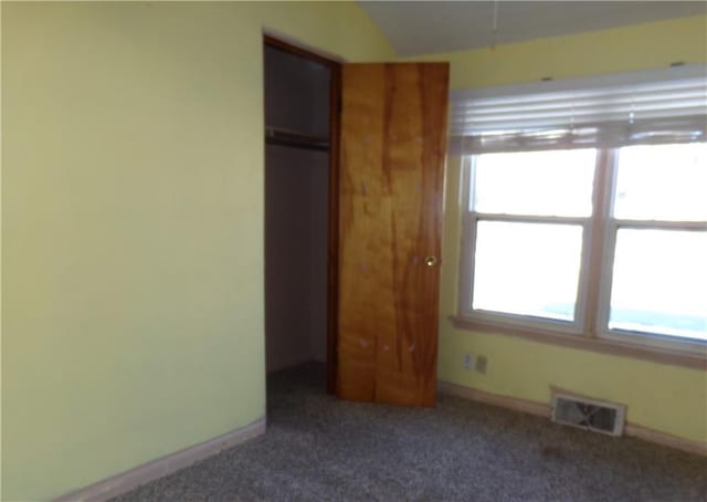 unfurnished bedroom with baseboards, visible vents, and dark carpet