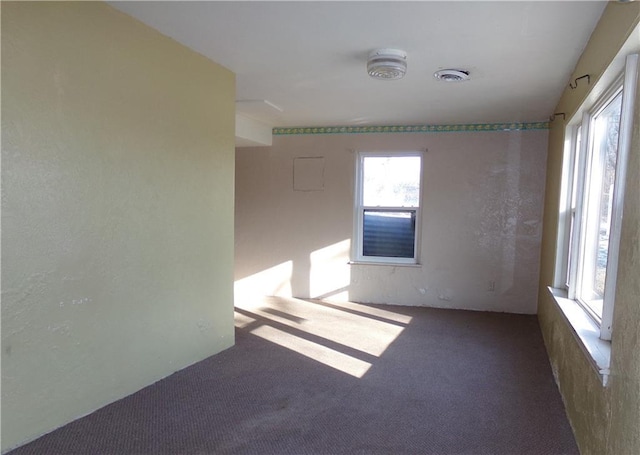 unfurnished room with dark colored carpet and visible vents