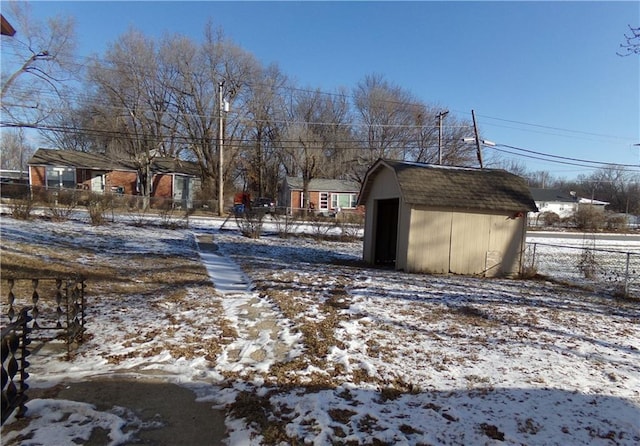 yard layered in snow with a storage shed, fence, and an outdoor structure