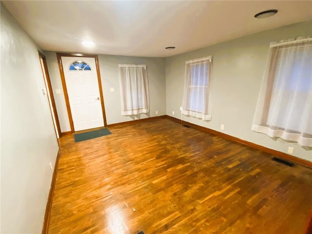 foyer featuring baseboards, visible vents, and wood finished floors