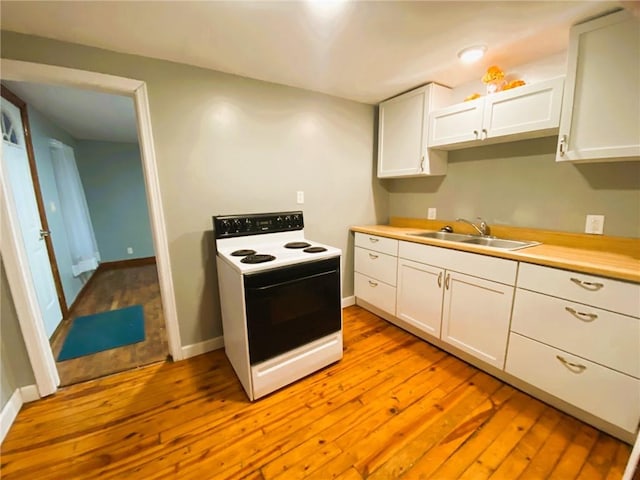 kitchen featuring light countertops, range with electric stovetop, a sink, and white cabinetry