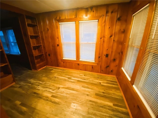 spare room with wood walls, wood finished floors, and baseboards