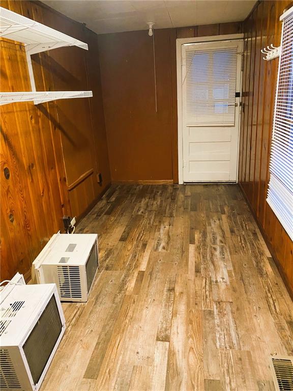 empty room featuring visible vents, wooden walls, and wood finished floors